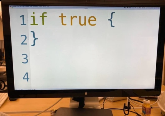 Picture of a computer monitor showing a text editor with the code "if true {}". The font size is so big the code takes most of the width of the monitor.