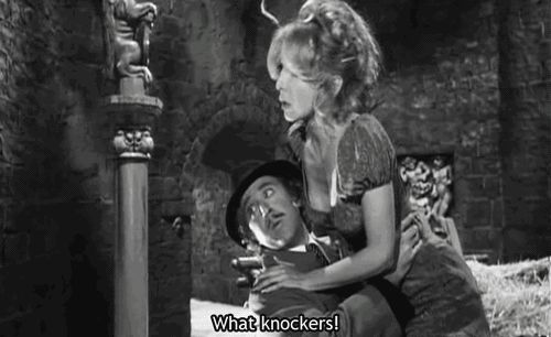 Screenshot from the film "Young Frankenstein" in which Gene Wilder is admiring the oversized ornamental knockers on a castle door and saying "what knockers!" while carrying Teri Garr, whose boobs are very near his face.